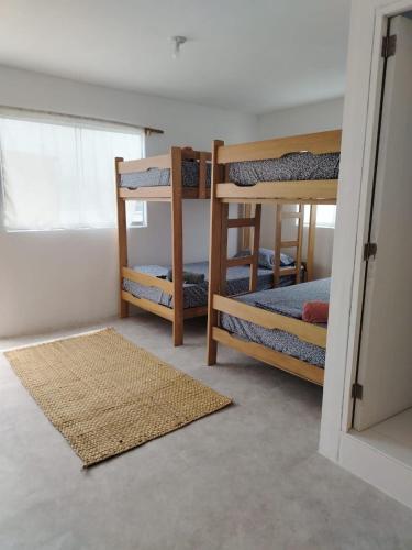 a room with three bunk beds and a rug at Cabañas Punta Negra in Punta Negra