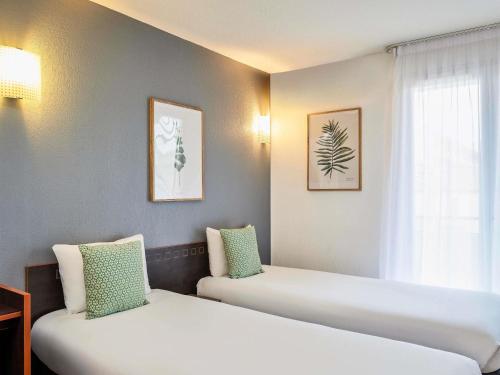 a room with two beds and a window at Aparthotel Adagio Access Nice Garibaldi in Nice