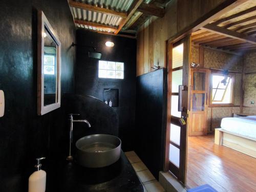 a black bathroom with a tub in a room at Tetebatu Sasak House Bungalow in Tetebatu