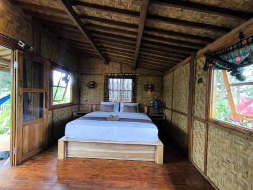 a bedroom with a bed in a room with windows at Tetebatu Sasak House Bungalow in Tetebatu