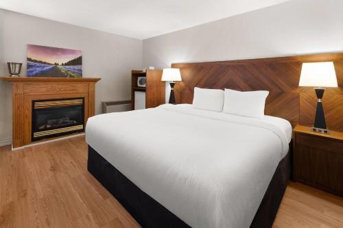 a bedroom with a large bed and a fireplace at Ramada by Wyndham Arnprior in Arnprior