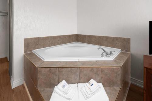 a bath tub with a sink in a room at Ramada by Wyndham Arnprior in Arnprior