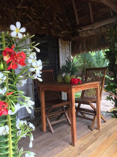 a table and two chairs on a porch with flowers at Oneta Resort in Ono Island