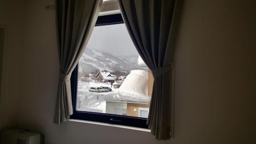 a window with a view of a snow covered mountain at Uchimaru Hakuba in Hakuba