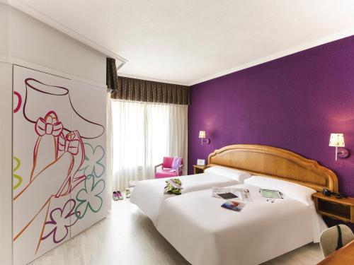 a hotel room with two beds and a purple wall at Hotel Ibis Styles La Rioja Arnedo in Arnedo