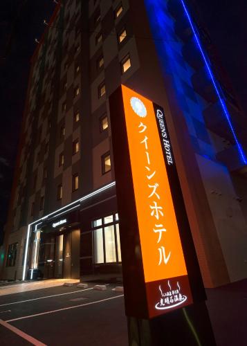 an orange sign on a pole in front of a building at Queens Hotel Chitose in Chitose