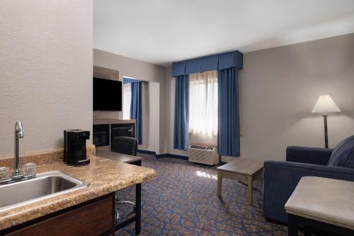a hotel room with a sink and a living room at Baymont by Wyndham Waukesha in Waukesha