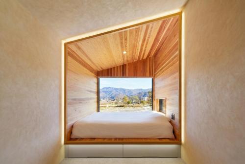 a bed in a room with a large window at Reposer Hakuba Hotel and Offsite Villa in Hakuba