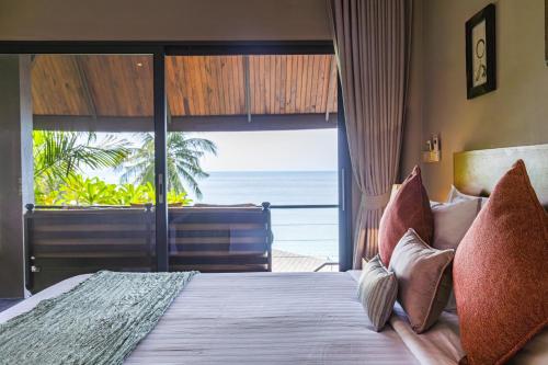 a bedroom with a bed with a view of the ocean at Beyond The Blue Horizon Boutique Bungalows in Haad Chao Phao
