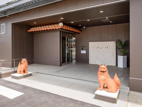 two statues of cats in front of a building at Comfort Hotel ERA Ishigaki Island in Ishigaki Island