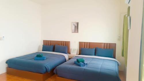 two beds with blue pillows in a room at Pai Town Home in Pai