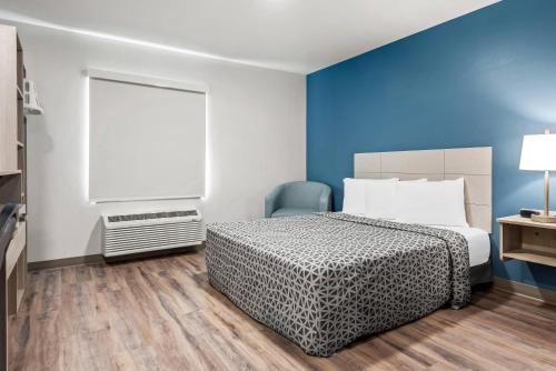 a bedroom with a bed and a blue wall at WoodSpring Suites Lancaster North in Lancaster