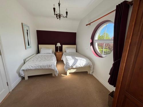 two beds in a room with a window at White House tree view in Drumshanbo