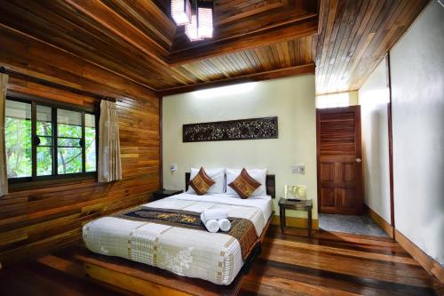 a bedroom with a bed in a room with wooden walls at Khao Sok Las Orquideas Resort in Khao Sok