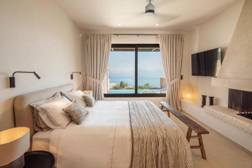 a bedroom with a large bed with a large window at AÁSHNA Suites and Residences in Vaia