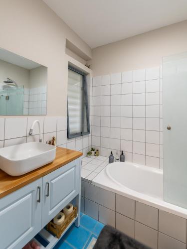 a white bathroom with a tub and a sink at המקום של נטע in Mitzpe Hila