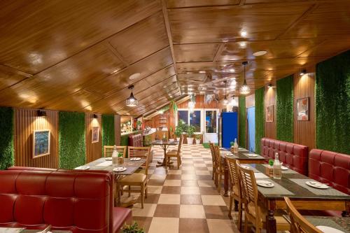 a restaurant with tables and chairs and green walls at Treebo Roshan House Near Mcleodganj in McLeod Ganj