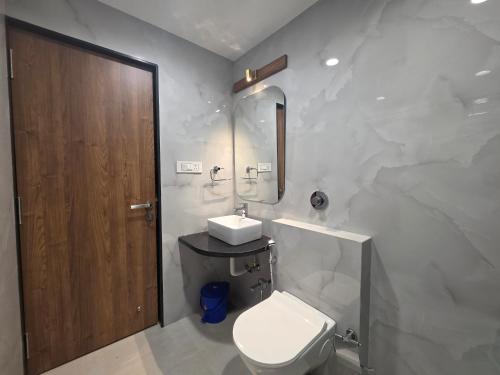 a white bathroom with a toilet and a sink at New Vyankatesh in Mahabaleshwar