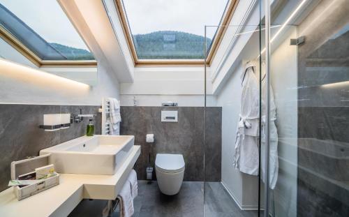 a bathroom with a sink and a toilet and a skylight at Hotel Bellerive in Zermatt