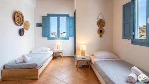 two beds in a room with two windows at In Alto in Plaka Milou