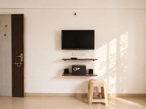 a room with a tv on a wall with a stool at Sk Holiday Apartment in Alibaug