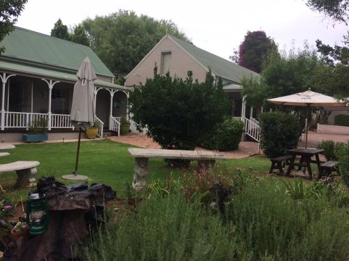 a patio with an umbrella and a picnic table and an umbrella at HouseMartin Lodge & Self Catering in De Rust