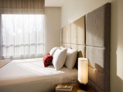 a bedroom with a bed with white pillows and a window at The Sebel Launceston in Launceston