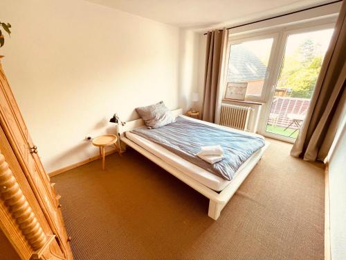 a bedroom with a bed and a large window at Weener - City Apartment mit Garten in Weener