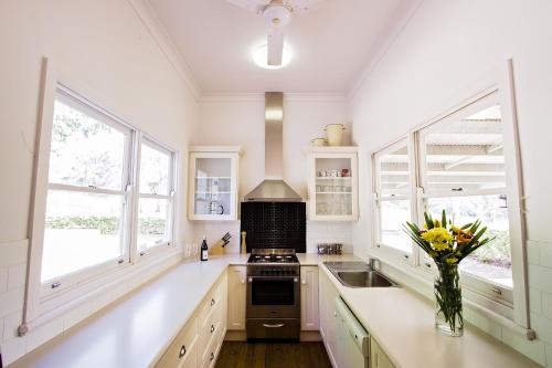 a kitchen with white counters and windows and a vase of flowers at Pooles Rock Vineyard Accommodation in Pokolbin