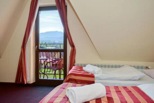 two beds in a room with a view of a balcony at Willa za Wodą in Zakopane