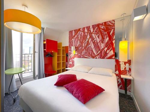 a bedroom with a white bed with red pillows at ibis Styles Paris La Défense Courbevoie in Courbevoie