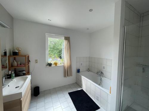 a white bathroom with a tub and a sink at Maison avec piscine à Dinant in Sorinnes