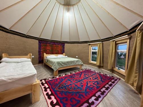 a room with two beds and a rug on the floor at Bosogo Yurt camp in Bokonbayevo