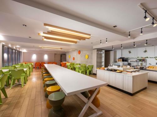 a cafeteria with a large white table and green chairs at ibis Styles Kyoto Station in Kyoto