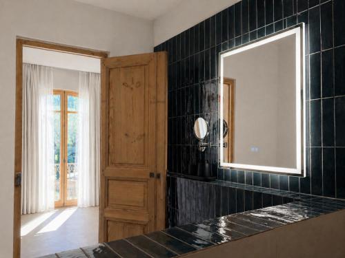 a bathroom with a mirror and a black tiled wall at LE PALMIER Aigues-Mortes Petite Camargue in Aigues-Mortes