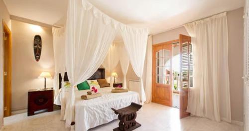 a bedroom with a white bed with a canopy at La Vijanera in Sant Jordi