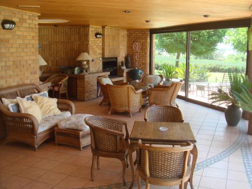 a living room with wicker chairs and tables at Bokmakierie Country Lodge in Ladysmith