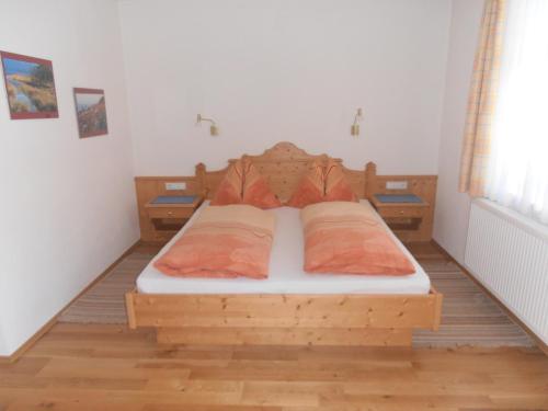 een slaapkamer met een houten bed met 2 kussens bij Puellgut in Flachau