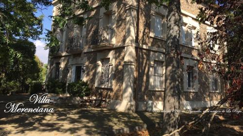 un viejo edificio con un árbol delante de él en Villa Merenciana en Agoncillo