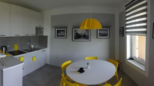 a kitchen with a white table and yellow chairs at Bajkowa Plaża - Muszelka in Gdańsk