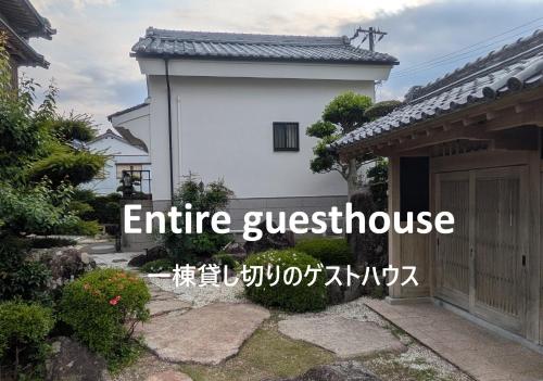 a white house with the words entire guest house at くまの蔵 Kumanokura inn Storehouse in Shingū