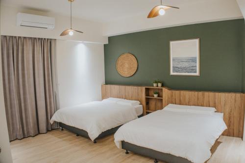 two beds in a room with green walls at Chungi Hotel 純吉民宿 咖啡 in Xincheng