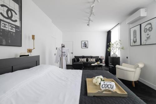 a white bedroom with a bed and a table with a cake at Villa COCO Chanel Kamer in Noordwijk
