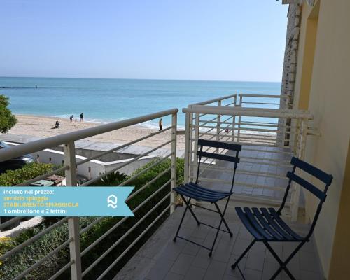 two chairs sitting on a balcony overlooking the beach at Sogni blu in Numana