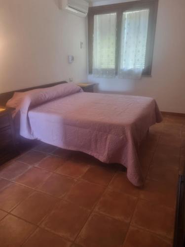 a bedroom with a bed with a pink blanket on it at Agriturismo Punta Su Cunventu in Narcao