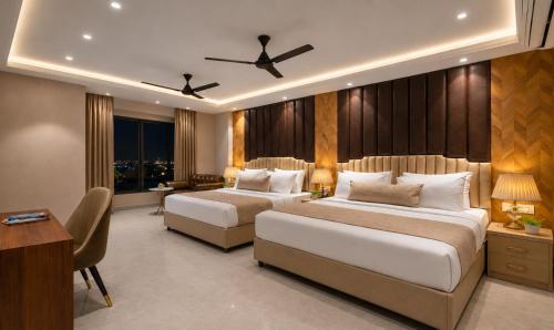 a hotel room with two beds and a desk at Hotel The Luxury Delhi Airport in New Delhi