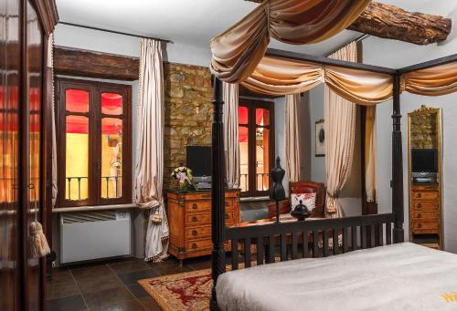 a bedroom with a canopy bed and a desk and window at Dimora I Manichei in Monforte dʼAlba