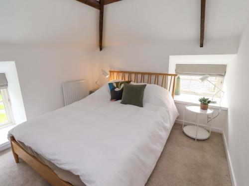 a bedroom with a large white bed and two windows at Snowdrop Cottage in Morpeth