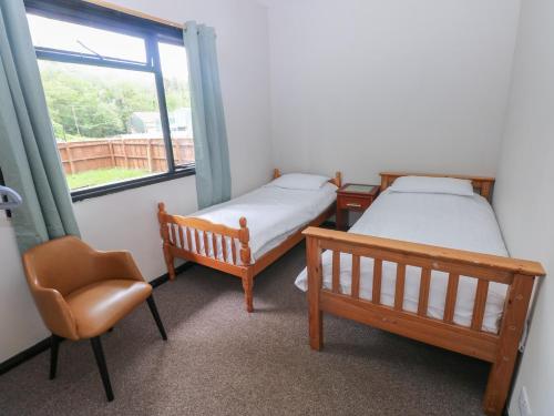 two beds and a chair in a room with a window at Cabin No 16 - Salt and Fern Cabins in Port Talbot