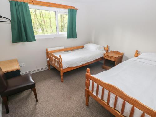 a bedroom with two beds and a chair and a window at Cabin No 11 - Salt and Fern Cabins in Port Talbot